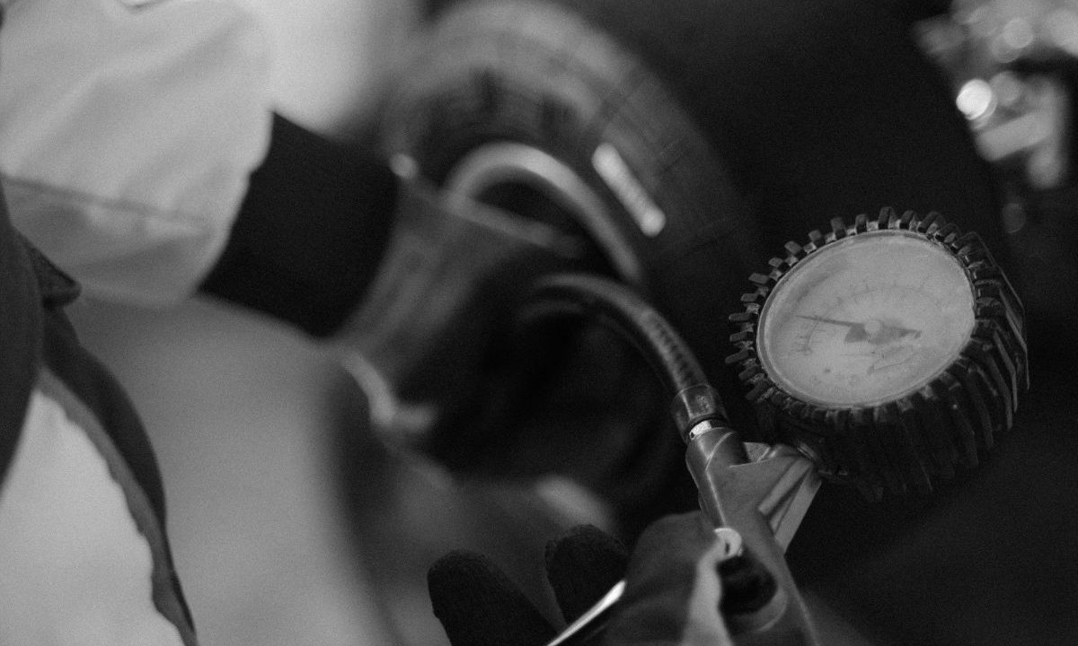 Checking car tire pressure with a gauge on the wheel