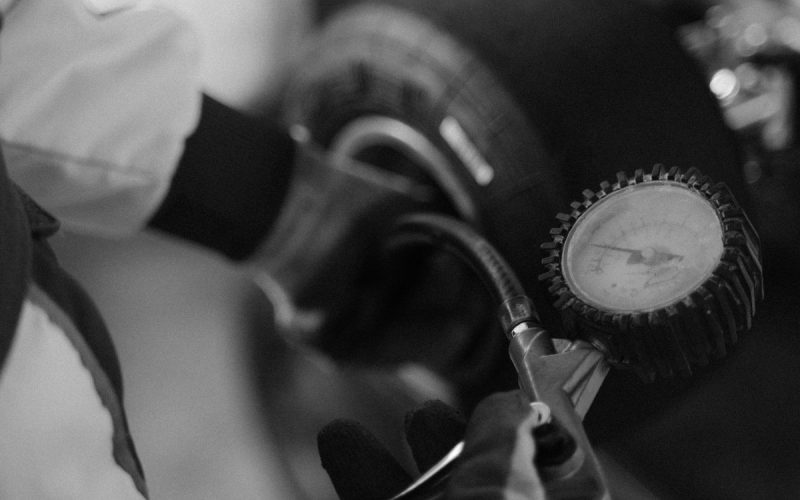 Checking car tire pressure with a gauge on the wheel